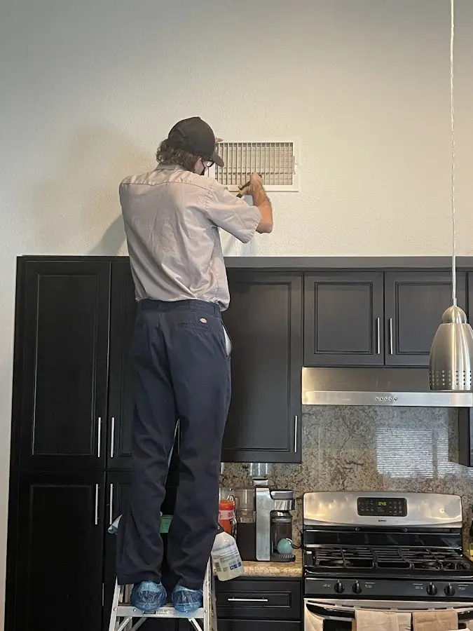 Technician inspecting an air vent during HVAC service in Laketon